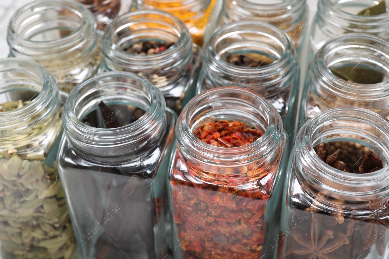 Photo of Different spices in glass jars on table, closeup