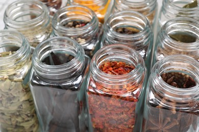 Different spices in glass jars on table, closeup