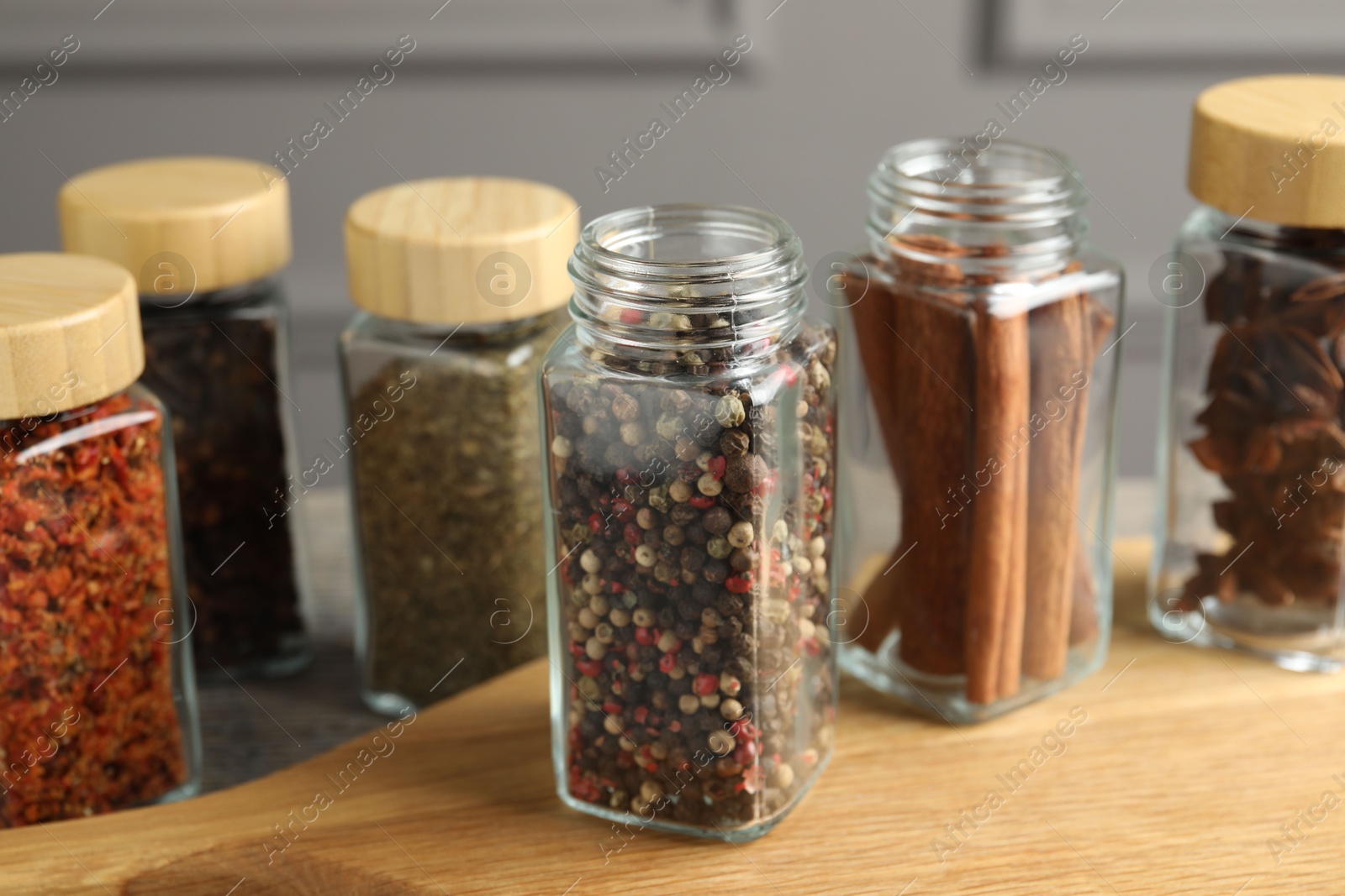 Photo of Different spices in glass jars on wooden table