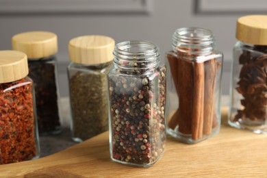 Photo of Different spices in glass jars on wooden table