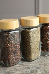 Different spices in glass jars on wooden table