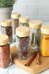 Photo of Different spices in glass jars on white marble table