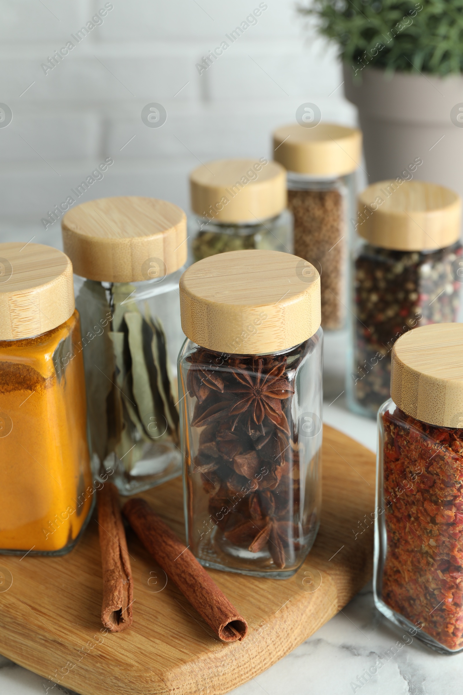 Photo of Different spices in glass jars on white marble table