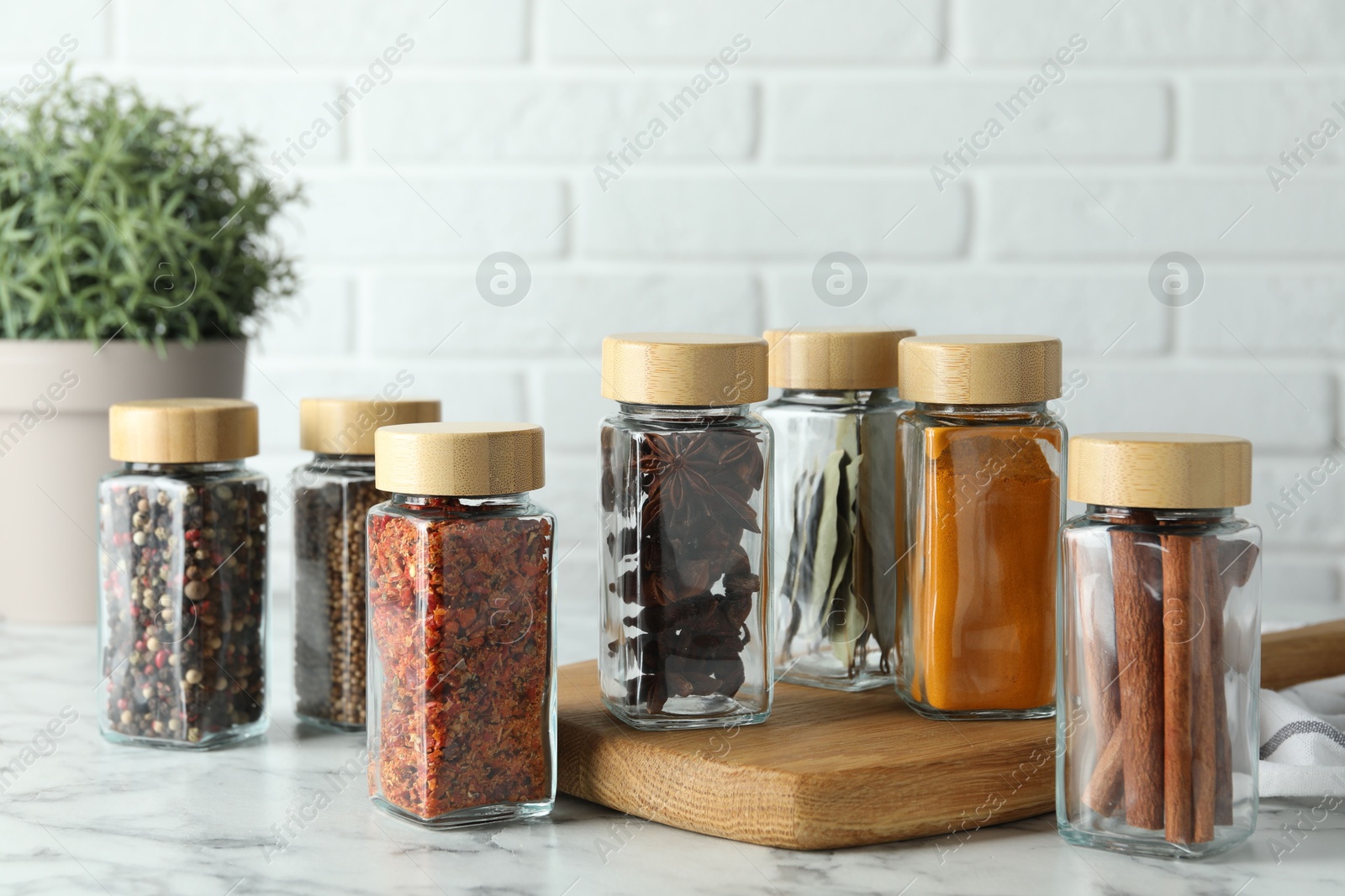 Photo of Different spices in glass jars on white marble table