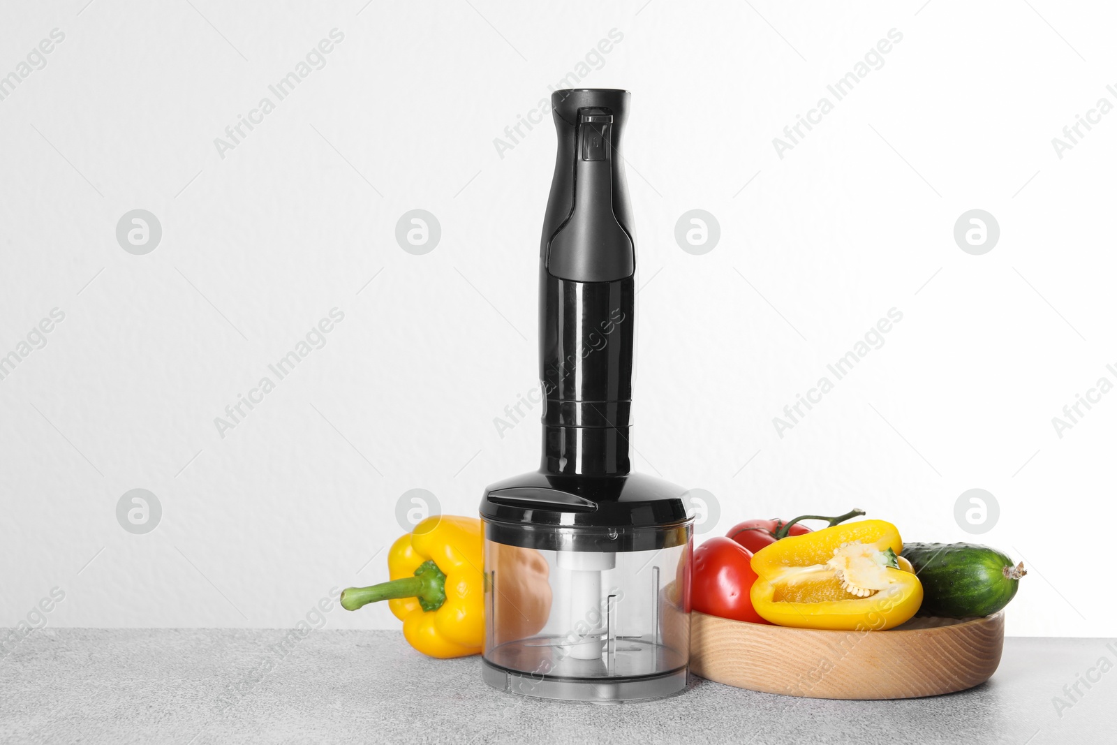 Photo of Hand blender kit and fresh vegetables on gray table against white background, space for text