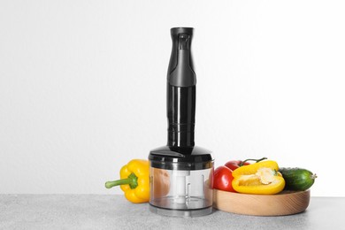 Photo of Hand blender kit and fresh vegetables on gray table against white background, space for text