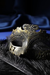 Beautiful carnival mask and feathers on blue fabric, closeup