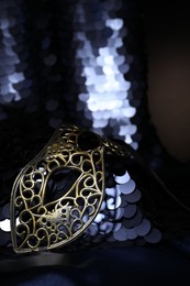 Beautiful carnival mask and fabric with golden sequins in darkness, closeup