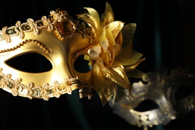 Photo of Beautiful carnival masks in darkness, closeup view