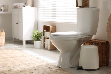 Photo of White toilet bowl and trash can in bathroom