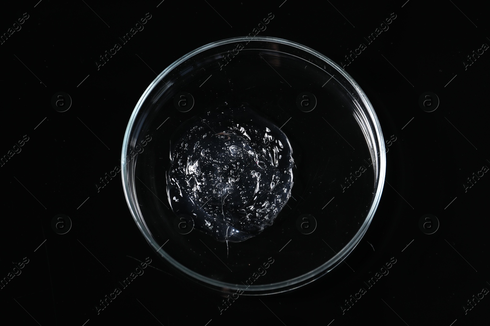 Photo of Petri dish with sample on black mirror surface, top view