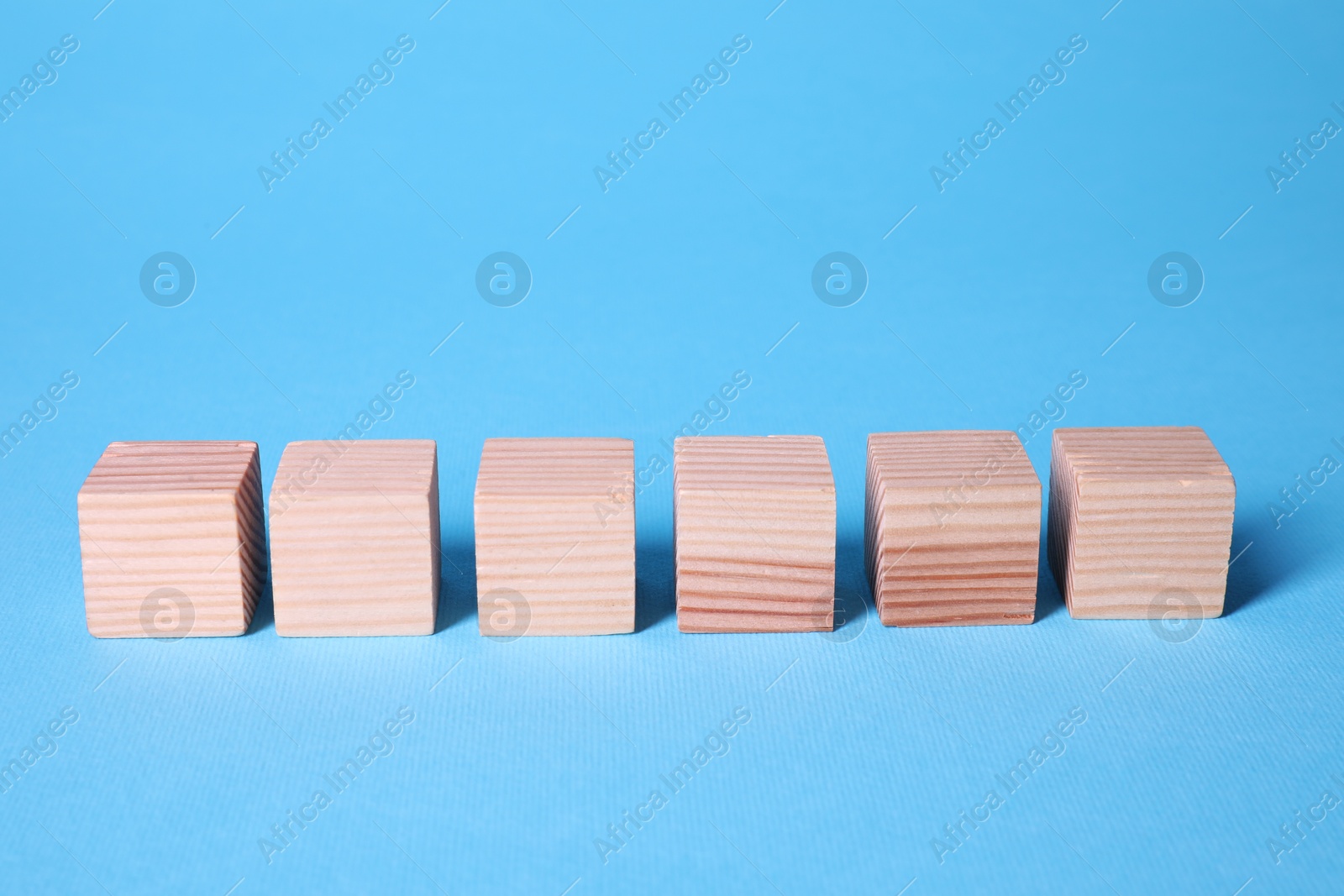 Photo of Many blank wooden cubes on light blue background