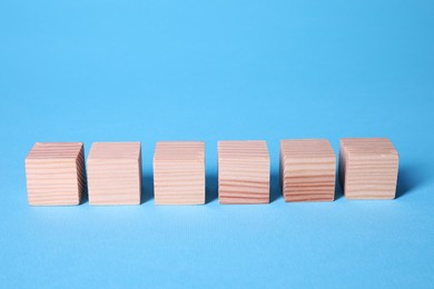 Photo of Many blank wooden cubes on light blue background