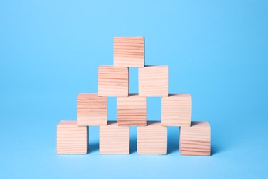 Photo of Many blank wooden cubes on light blue background