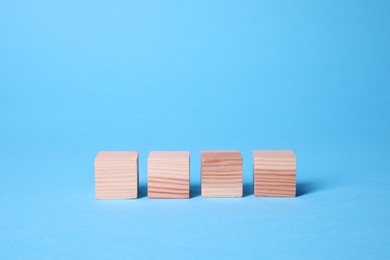 Photo of Many blank wooden cubes on light blue background