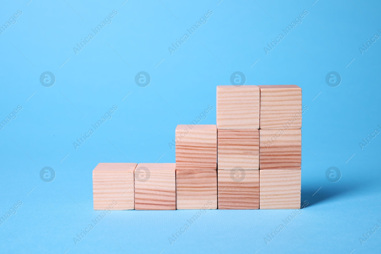 Photo of Many blank wooden cubes on light blue background