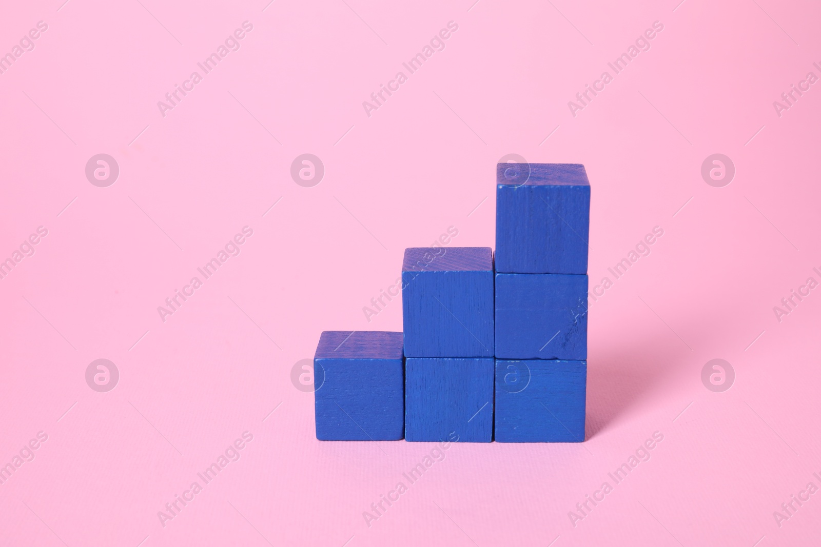 Photo of Many blank blue cubes on pink background, space for text