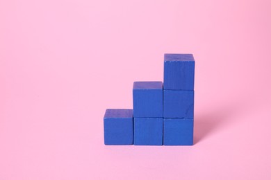 Photo of Many blank blue cubes on pink background, space for text