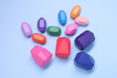 Photo of Many colorful balancing stones on light blue background, top view