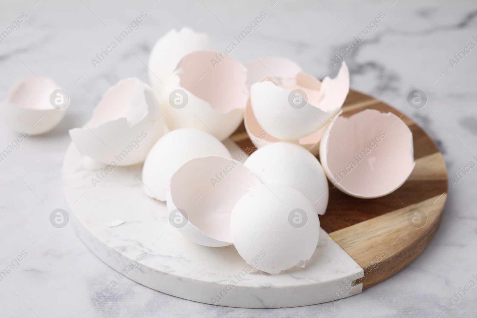 Photo of Broken eggshells on light marble table, closeup