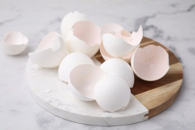 Photo of Broken eggshells on light marble table, closeup