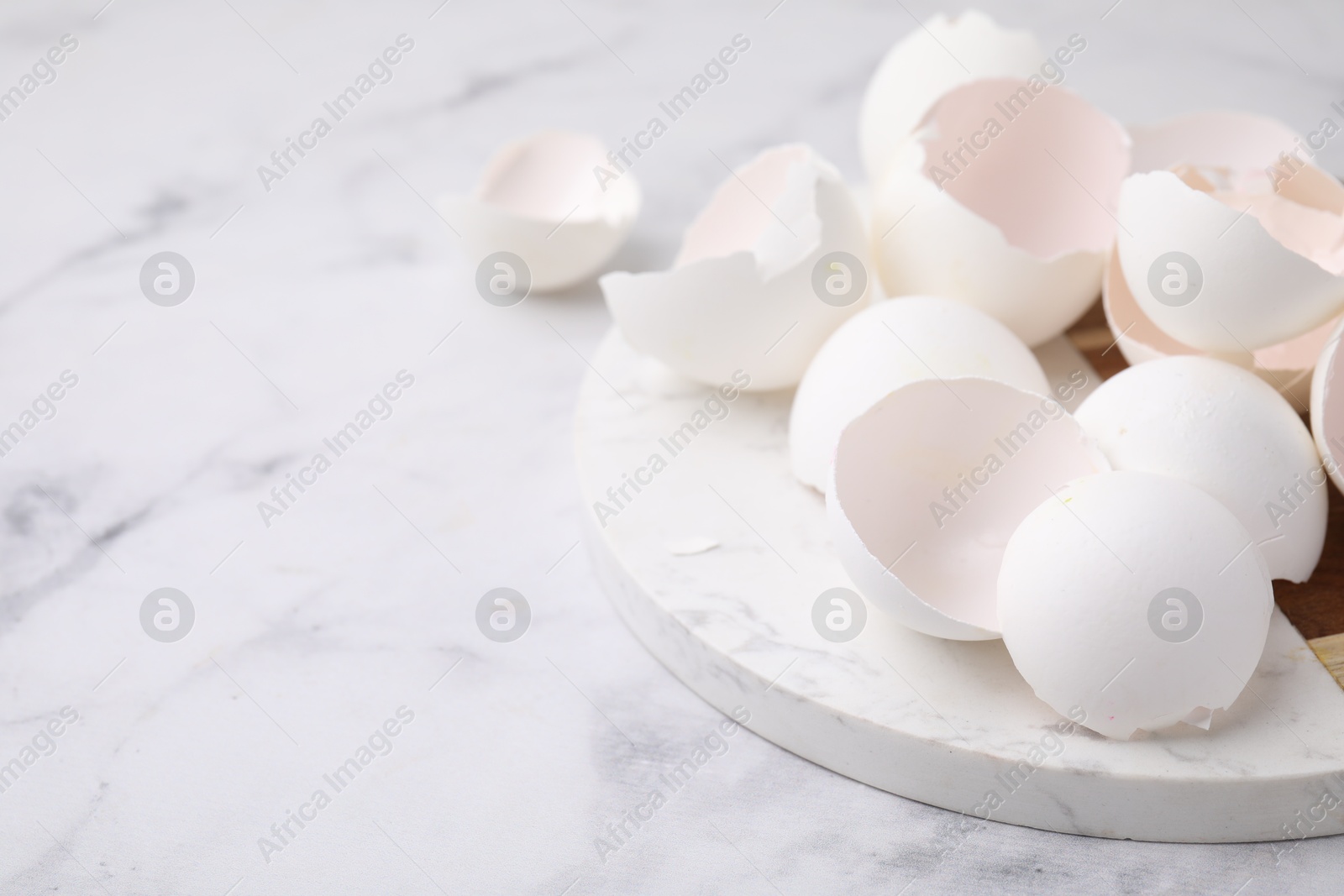 Photo of Broken eggshells on light marble table, closeup. Space for text