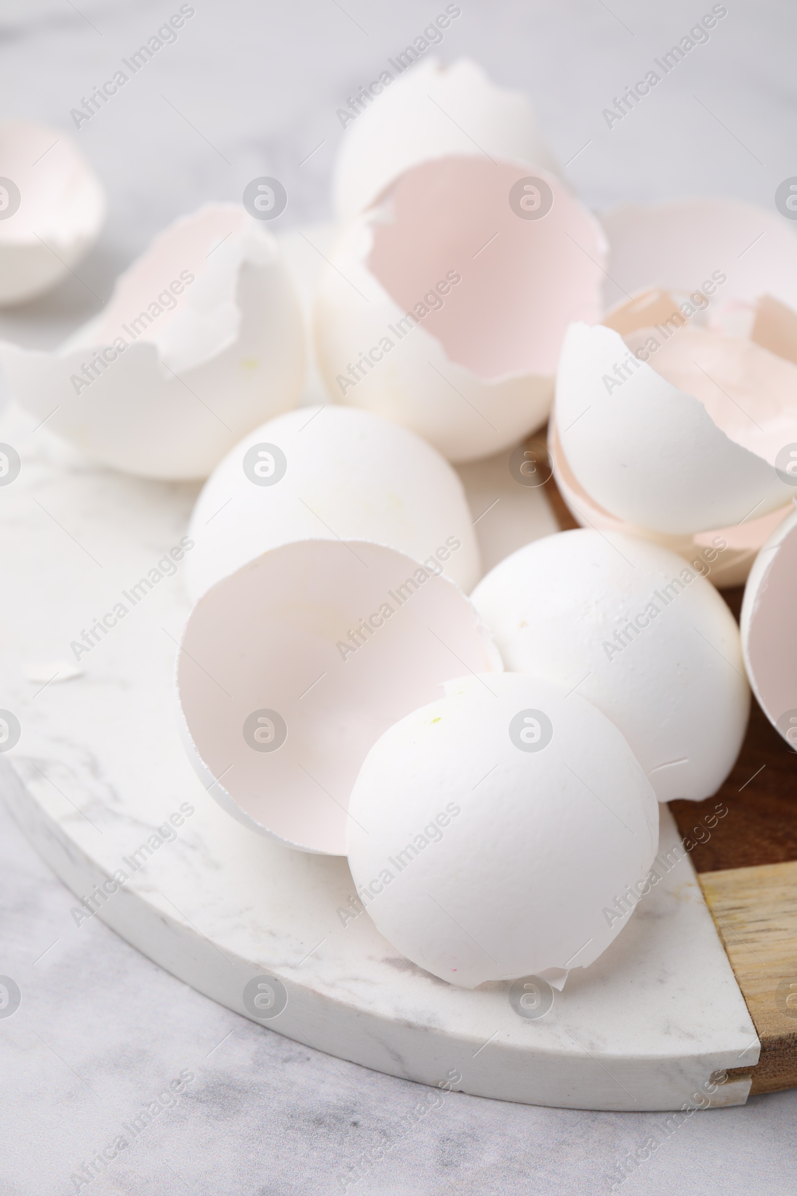 Photo of Broken eggshells on light marble table, closeup