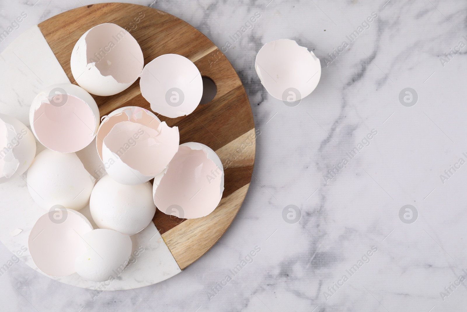 Photo of Broken eggshells on light marble table, top view. Space for text