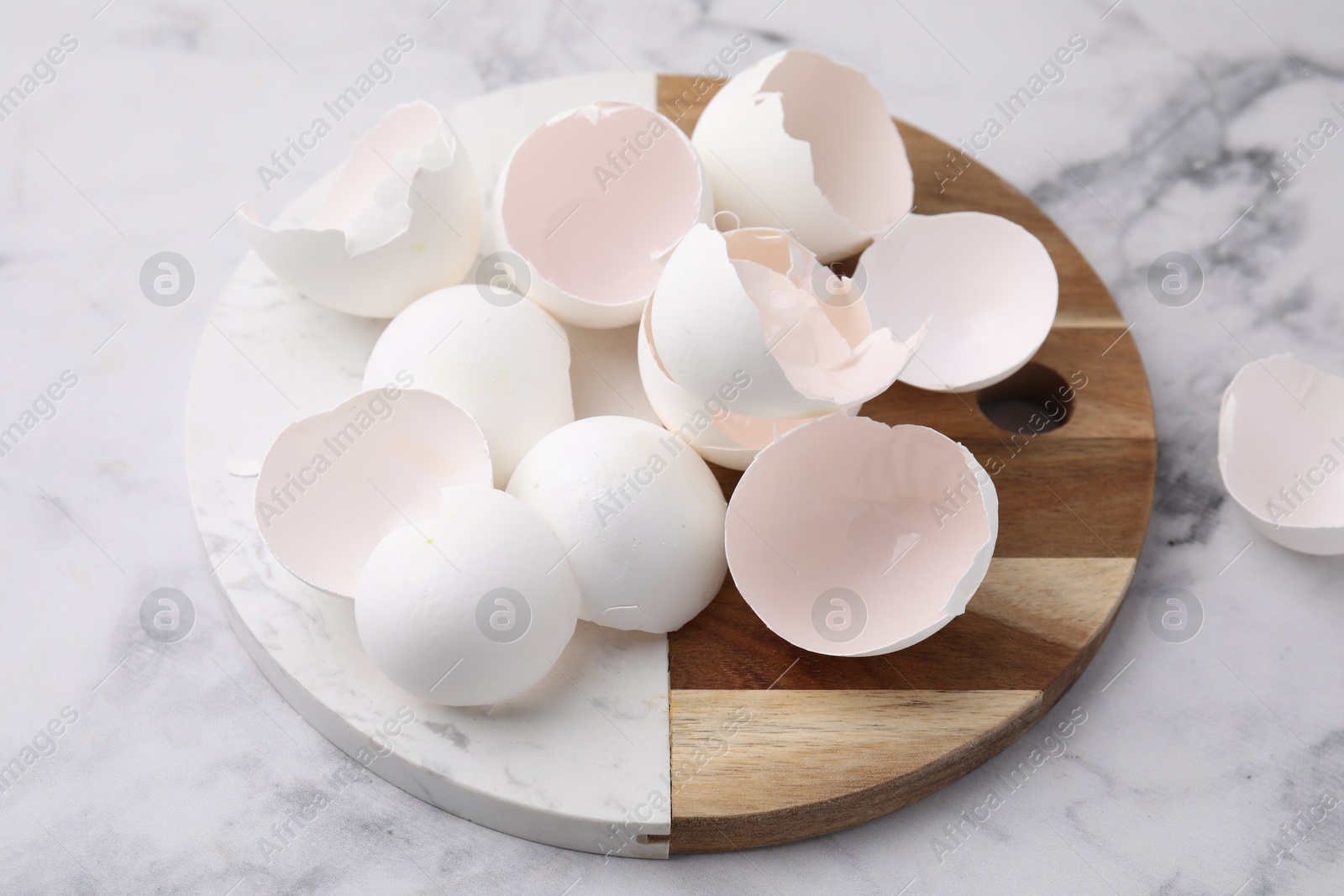 Photo of Broken eggshells on light marble table, closeup