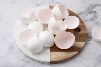 Photo of Broken eggshells on light marble table, closeup