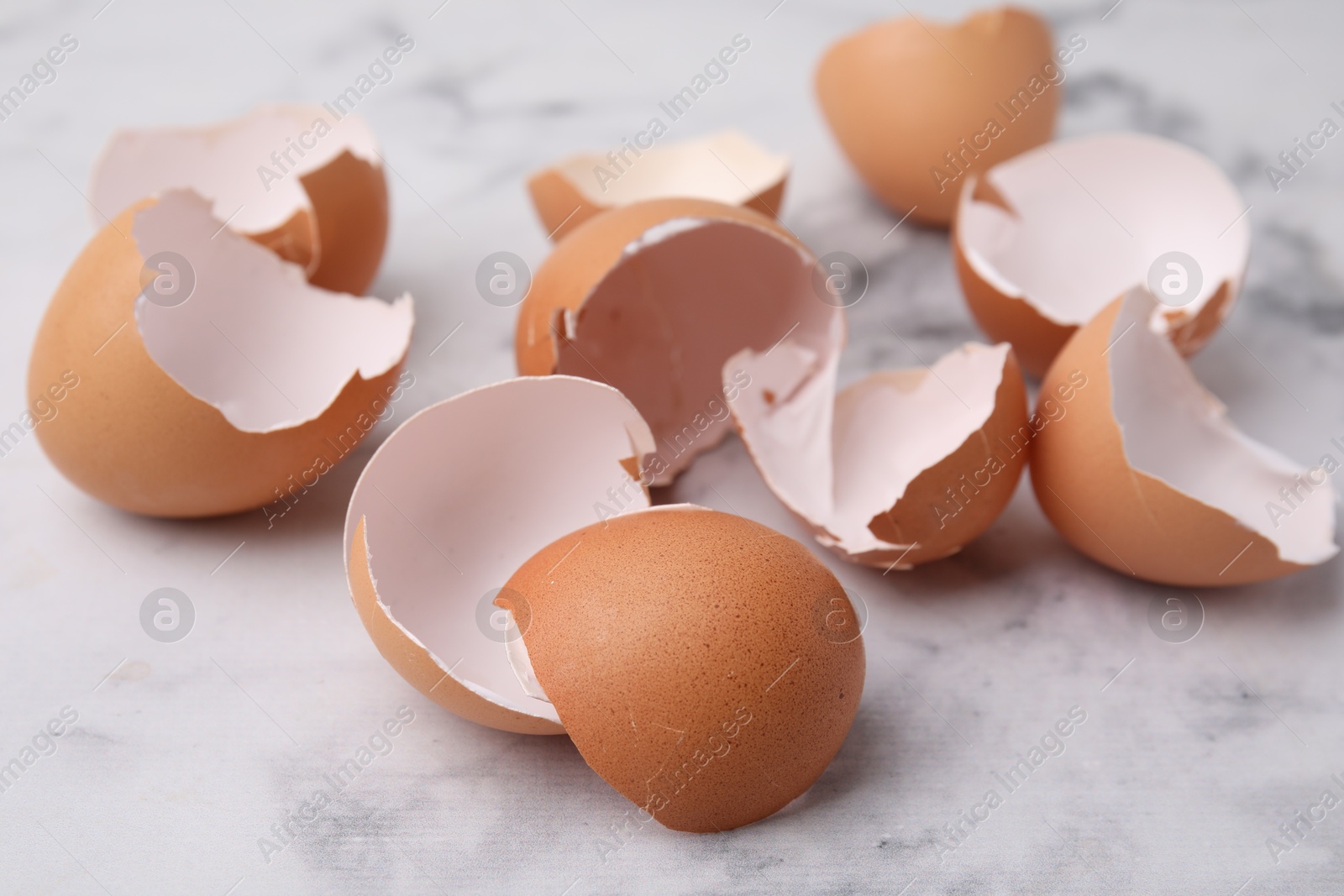 Photo of Broken eggshells on light marble table, closeup