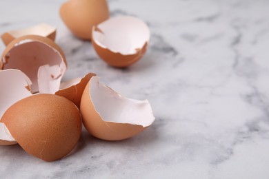 Photo of Broken eggshells on light marble table, closeup. Space for text