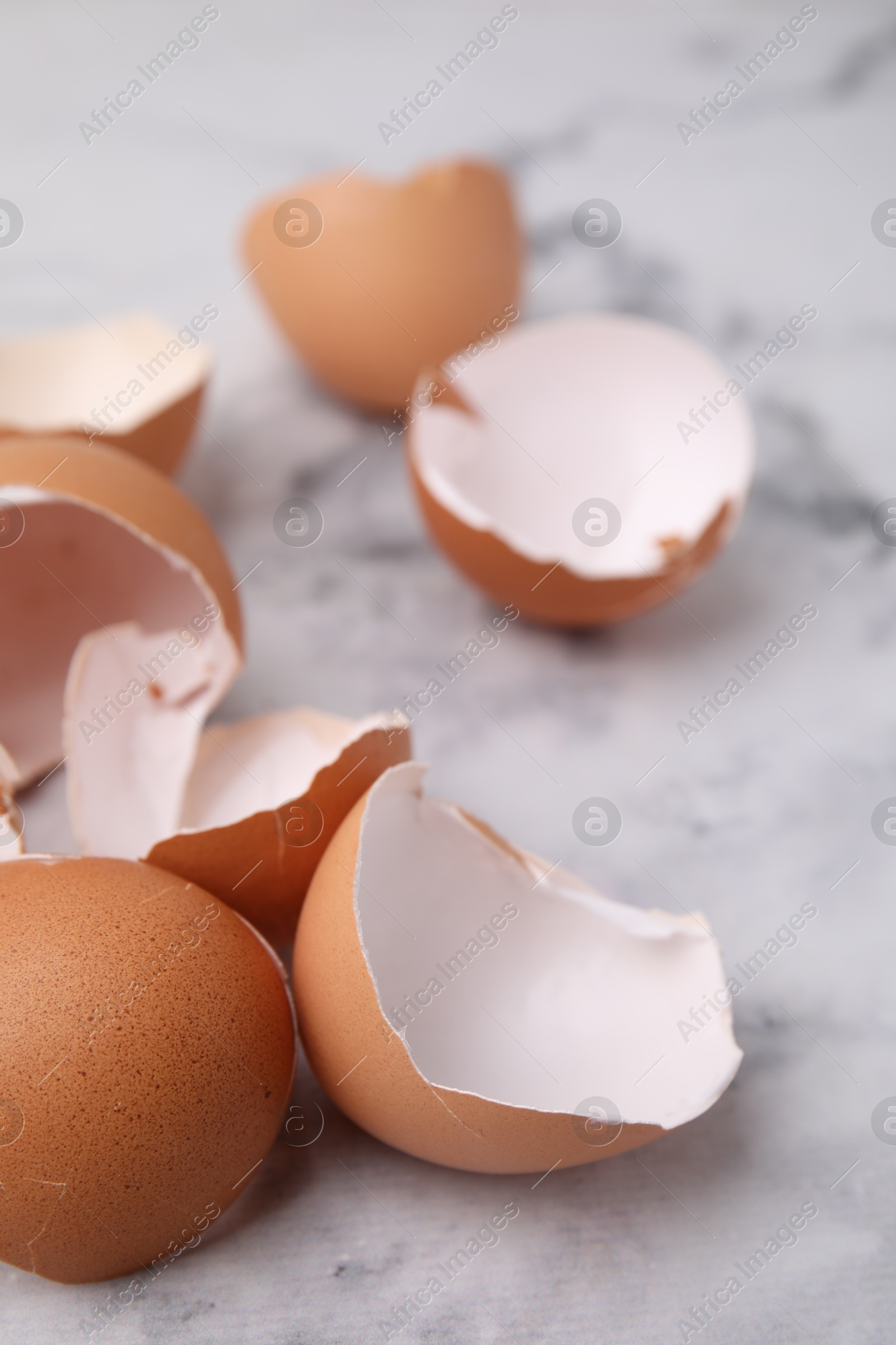 Photo of Broken eggshells on light marble table, closeup