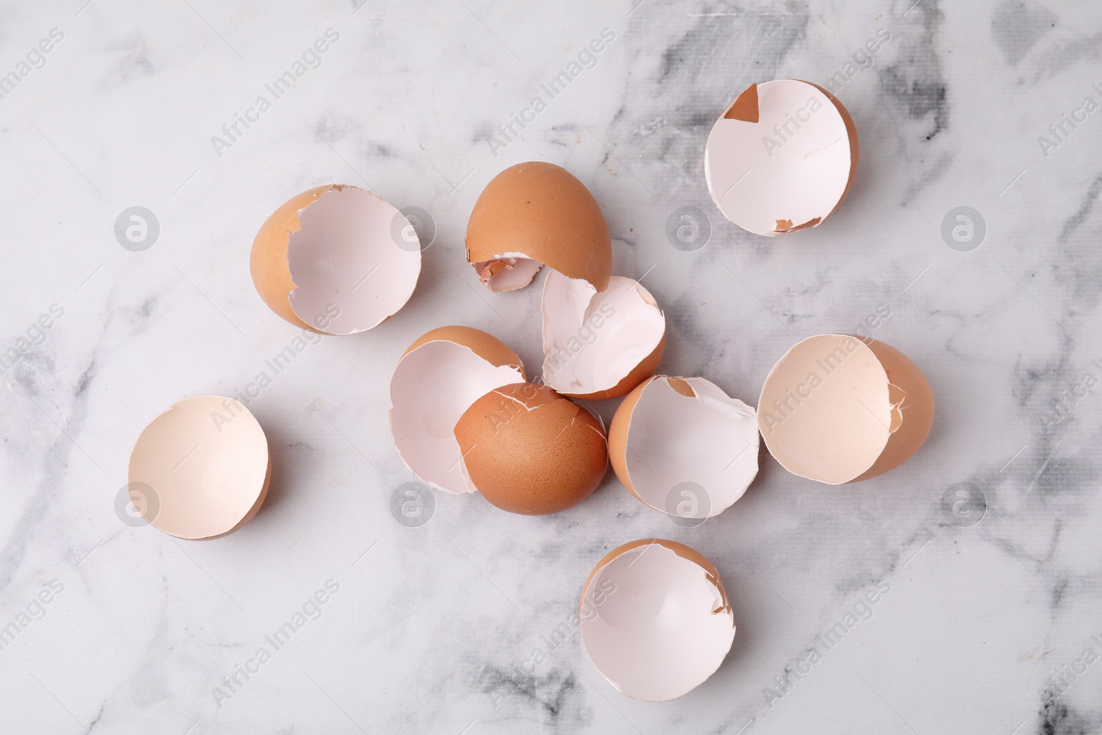 Photo of Broken eggshells on light marble table, top view