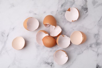 Photo of Broken eggshells on light marble table, top view