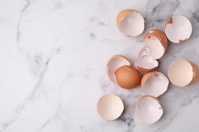 Photo of Broken eggshells on light marble table, top view. Space for text