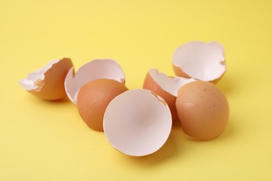 Photo of Pile of broken eggshells on yellow background, closeup