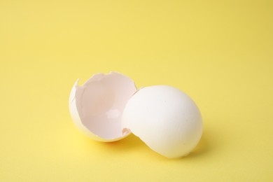 Photo of Pieces of broken eggshells on yellow background, closeup