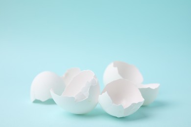 Photo of Pile of broken eggshells on light blue background, closeup