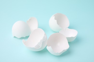 Photo of Pile of broken eggshells on light blue background, closeup