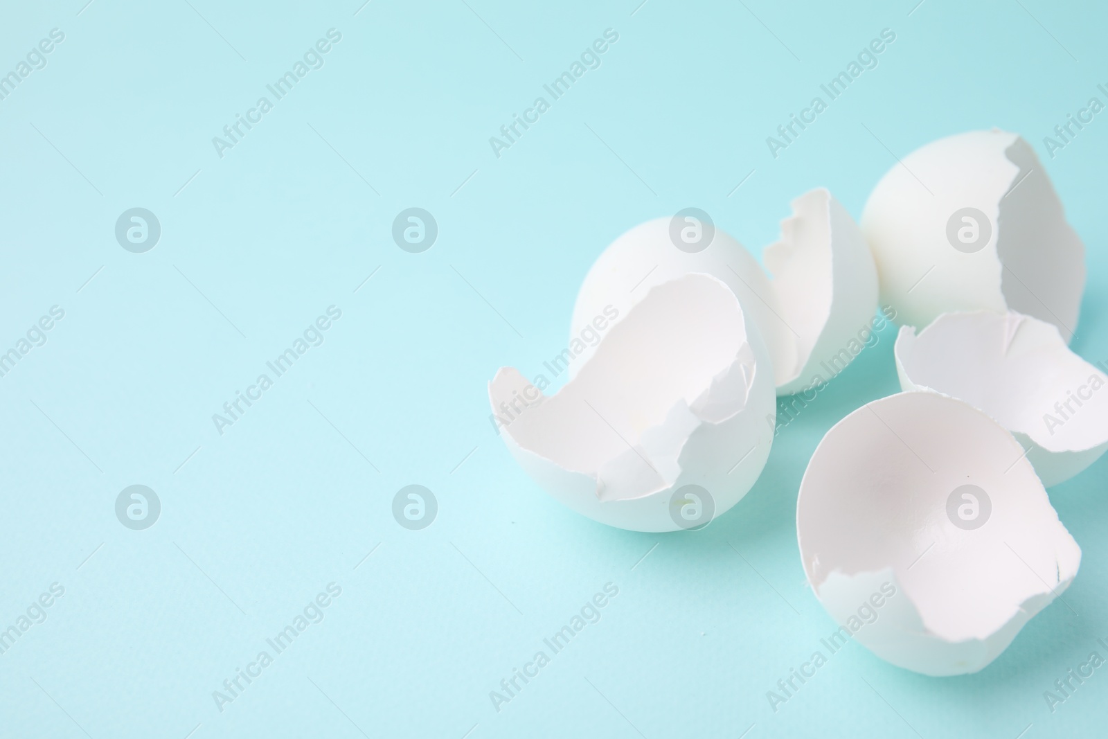 Photo of Broken eggshells on light blue background, closeup. Space for text