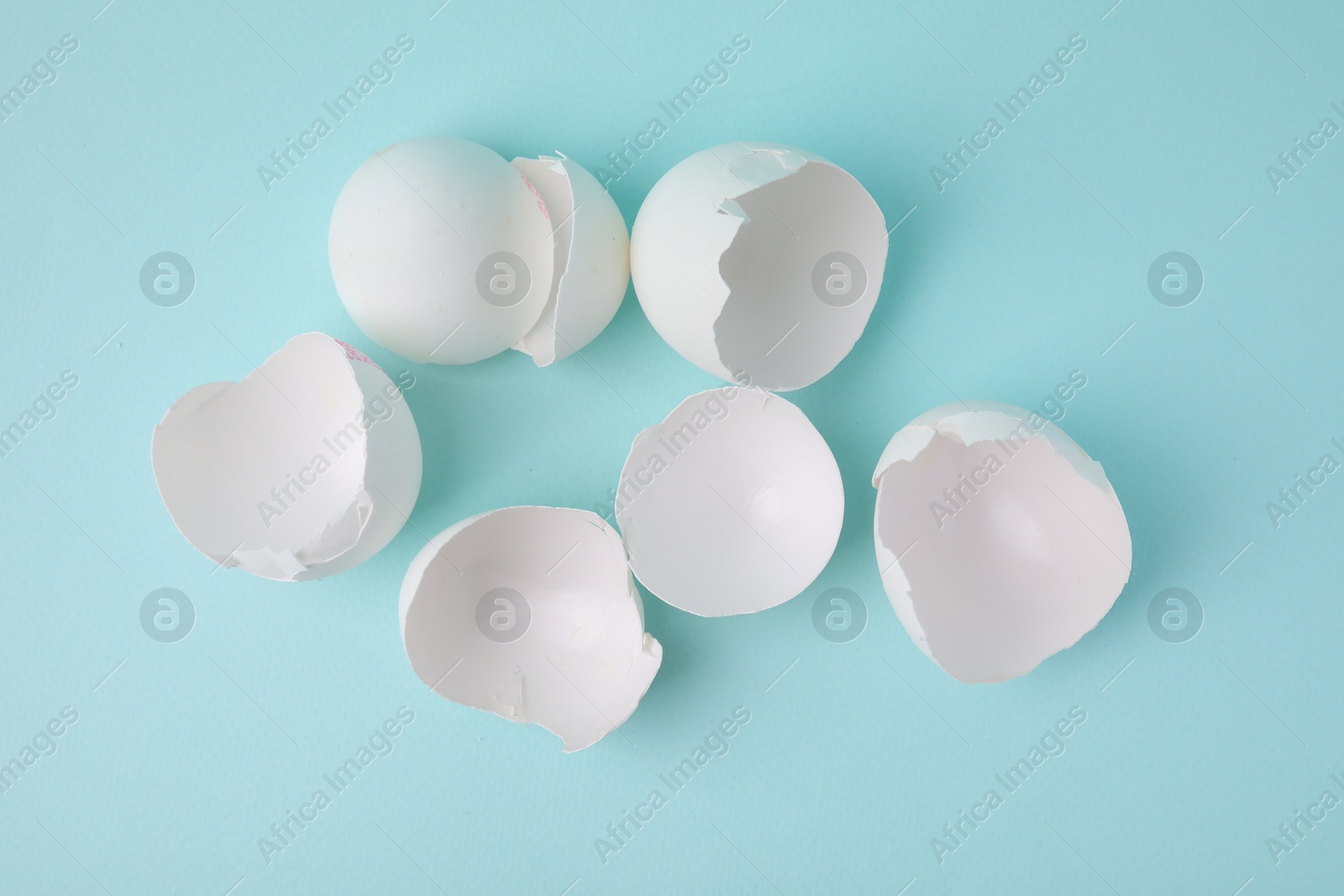 Photo of Broken eggshells on light blue background, top view