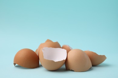 Photo of Pile of broken eggshells on light blue background, closeup