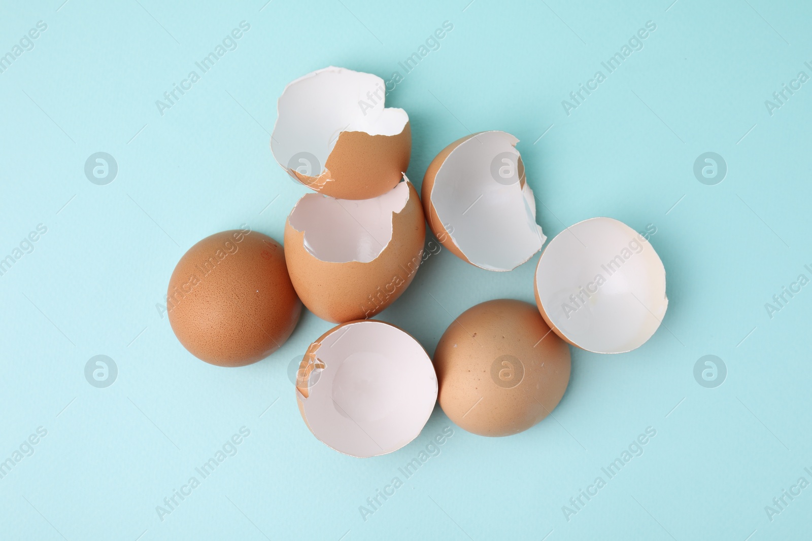 Photo of Broken eggshells on light blue background, top view