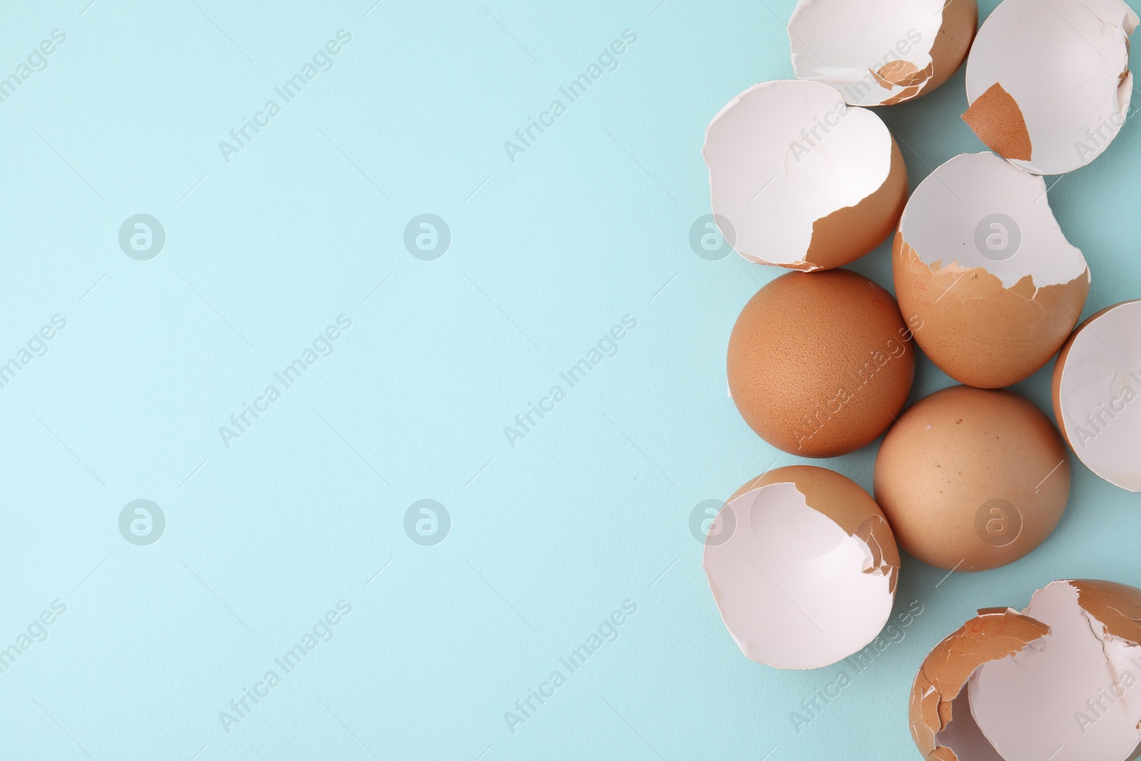 Photo of Broken eggshells on light blue background, top view. Space for text