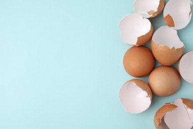 Photo of Broken eggshells on light blue background, top view. Space for text