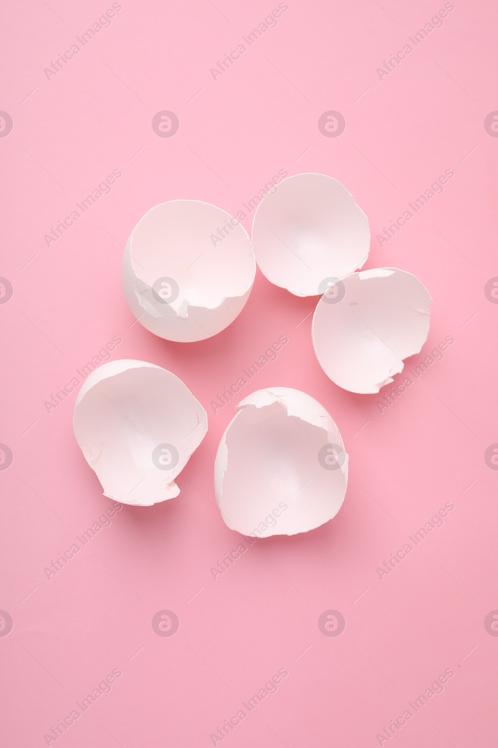 Photo of Broken eggshells on pink background, above view