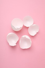 Photo of Broken eggshells on pink background, above view