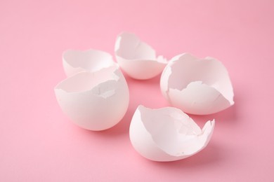 Photo of Pieces of broken eggshells on pink background, closeup