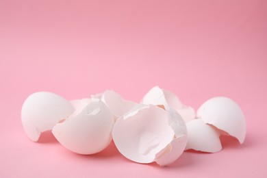 Photo of Pile of broken eggshells on pink background, closeup